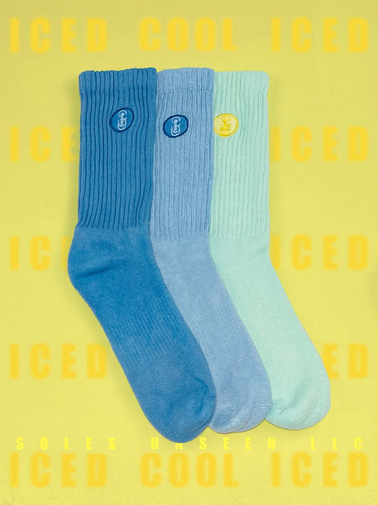 Three blue, light blue, and aqua crew socks with a yellow background.