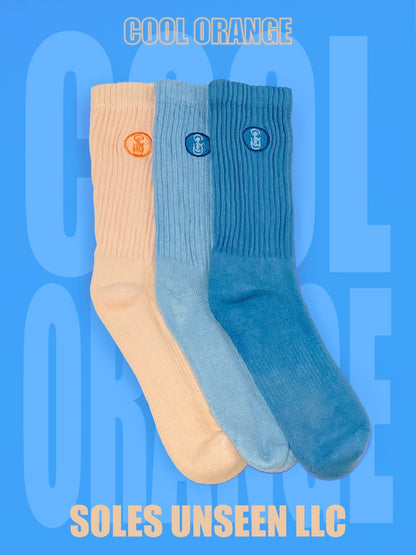 Three orange, light blue, and blue crew socks with blue background.