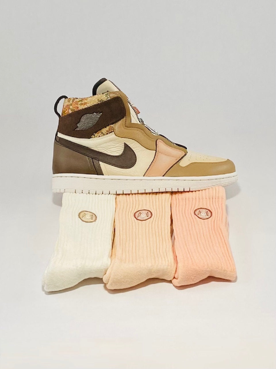 Custom painted brown shoes sitting on three pairs of cream and orange crew socks.