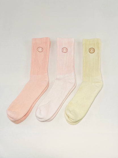 Three pink, light pink, and tan hand dyed crew socks.