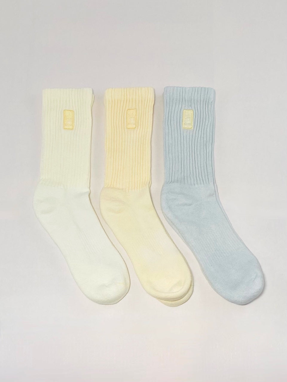 Three light yellow, yellow, and grey hand dyed crew socks.